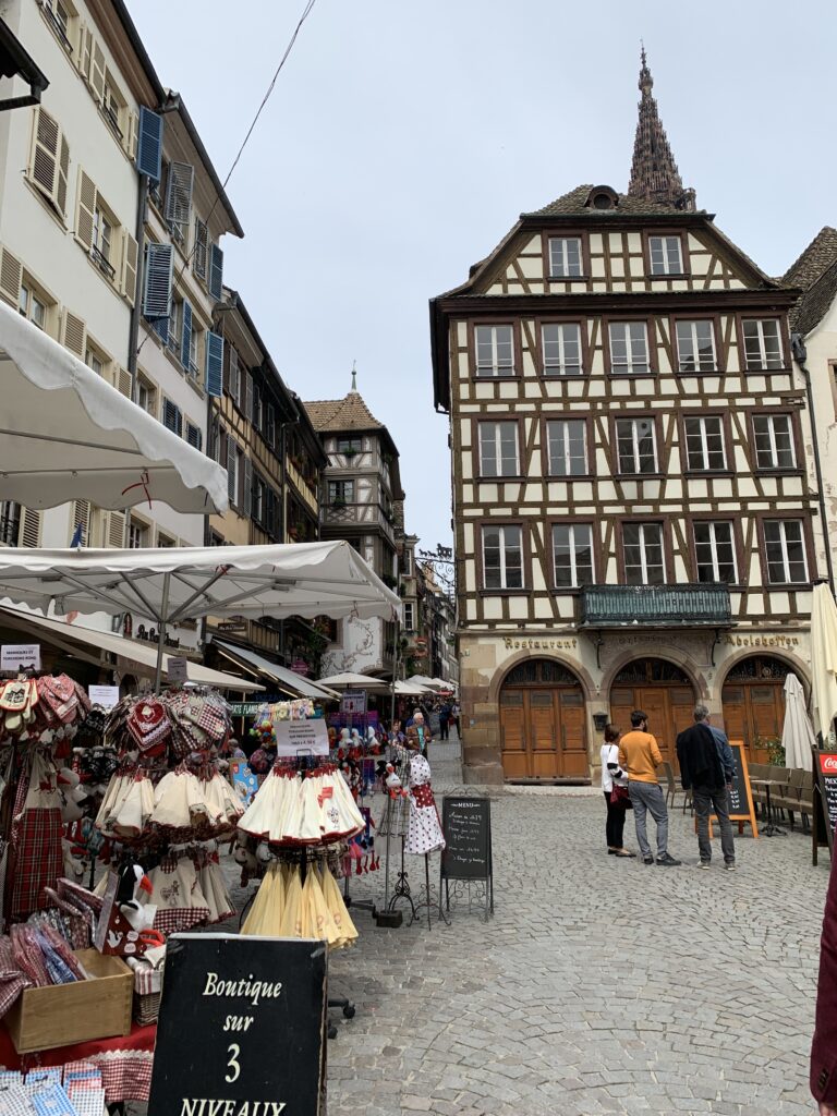 A souvenir store in Strasbourg sells traditional Alsace gifts. The souvenirs are sold both in the store and on the pedestrian only street in front of the shop, as seen in this photo.