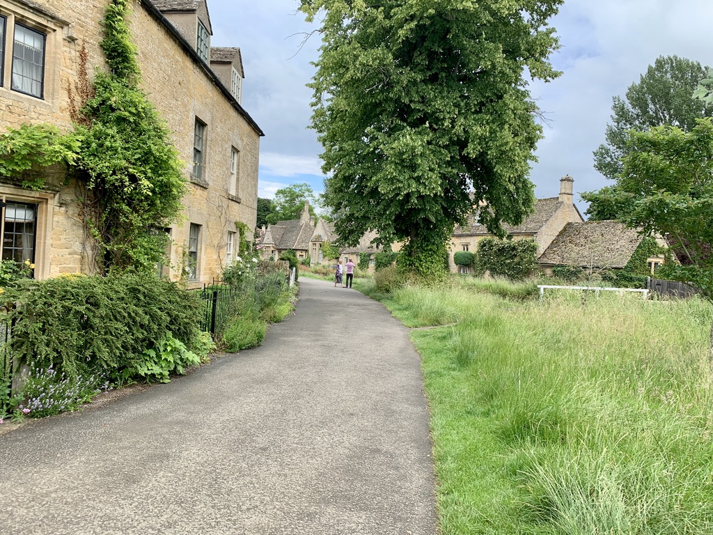 Paved path runs along a residential Cotswolds Village. Lower Slaughter is primarily residential areas.