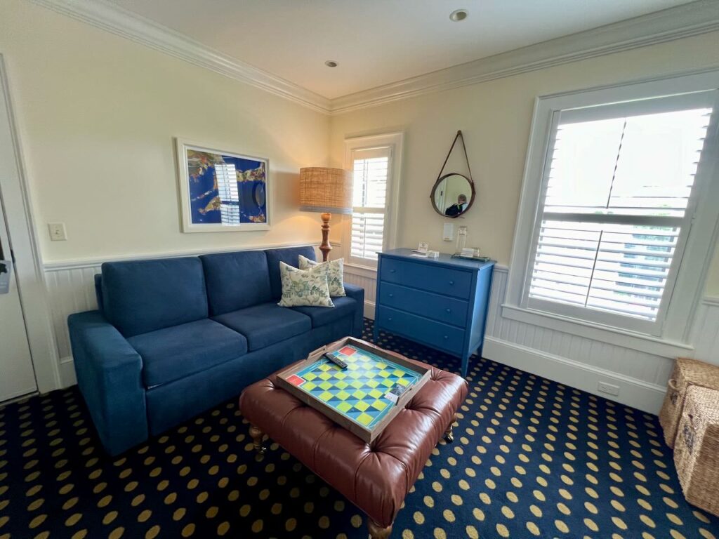 Blue sofa with leather ottoman. A large checker's board sits on the ottoman.